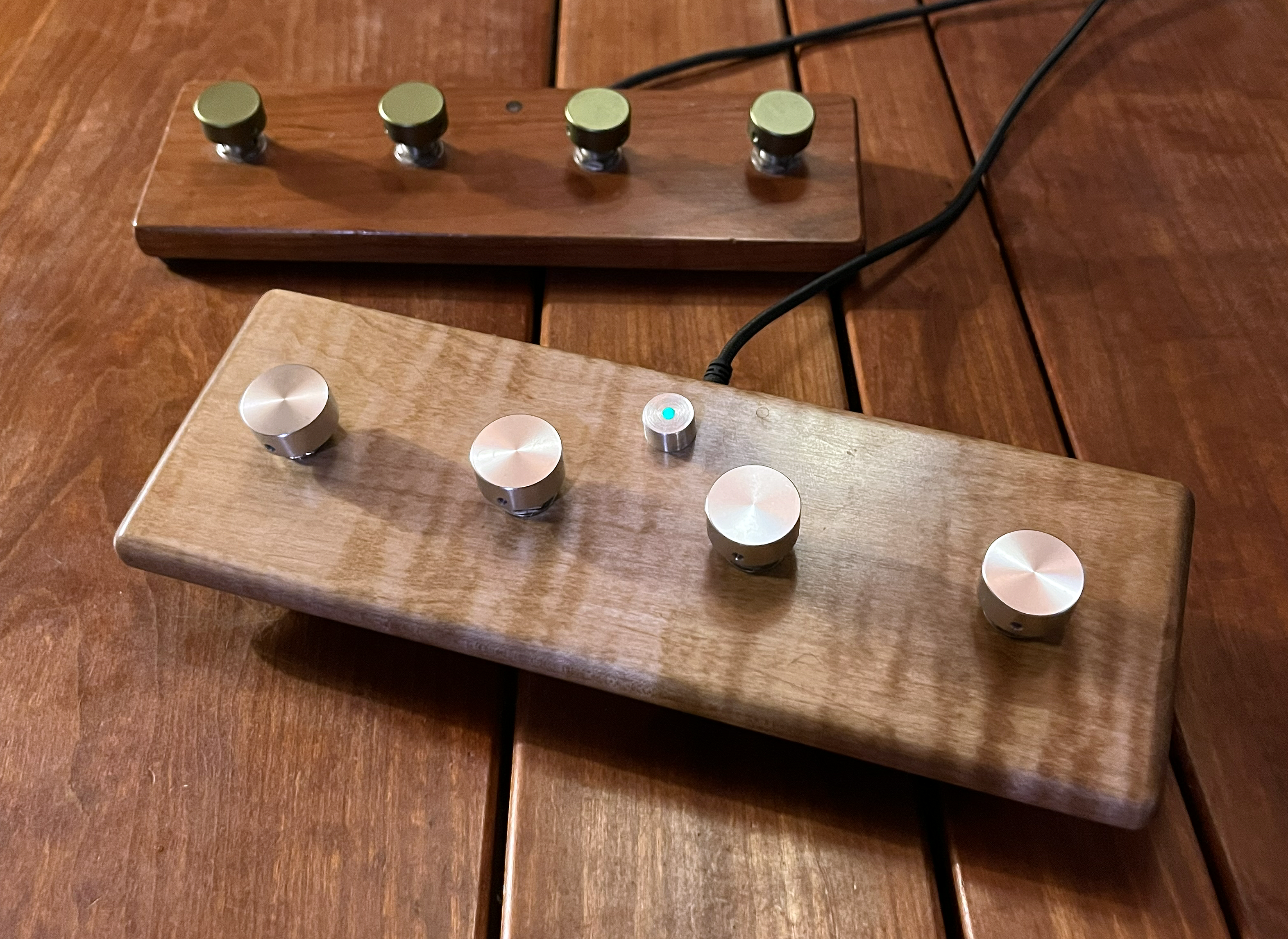 Tribe of Abraham programmable foot pedals — the current ESP32-S3 in curly maple and the original cherry slab, handmade at Ragamuffin Workshop
